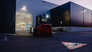 Ein Linde-Stapler, ausgerüstet mit dem Linde TruckSpot, fährt bei Dämmerung rückwärts aus der Halle.