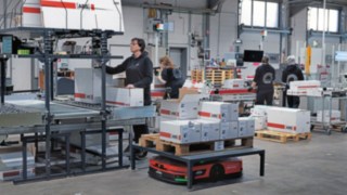 AMR-Linde-C-MATIC-in-der-Produktion-zusammen-mit-Mitarbeitenden