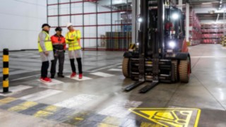 Beratungsgepräch mit mehreren Personen in der Werkshalle.